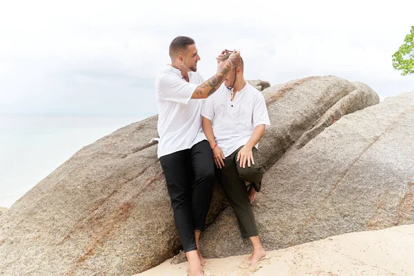 Homem colocando um colar em torno de seus parceiros gays pescoço em uma praia tropical — Fotografia de Stock