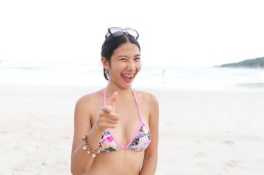 Dost canlısı bir kadın kumsalda kameraya bakarken yüzünü buruşturuyor.