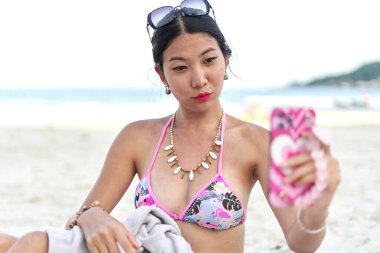 Sahilde sahneye çıkmadan önce seyyar ekranda kendini izleyen bir kadın.