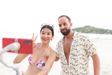 Flamalı ve turistin biri sahilde yaşarken zafer işareti yapıyor.