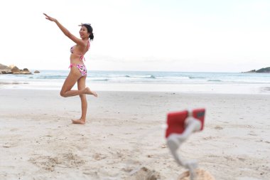 Gülümseyen etkili canlı performans sergilerken cep telefonunun önünde el kaldırıyor.