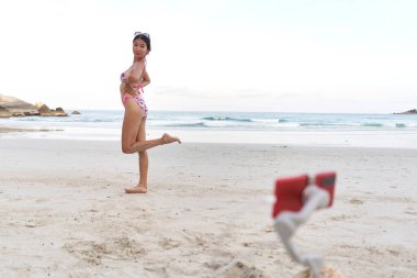 Canlı yayın yaparken bir cep telefonunun önünde poz veren Asyalı flamalı.