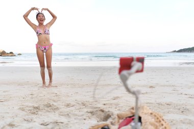 Kalp şeklini kollarıyla yapan flamalı cihaz cep telefonuyla canlı bir gösteri yapıyor.