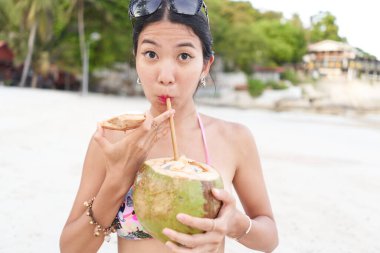 Sahilde doğal hindistancevizi suyu içen bir kadın..