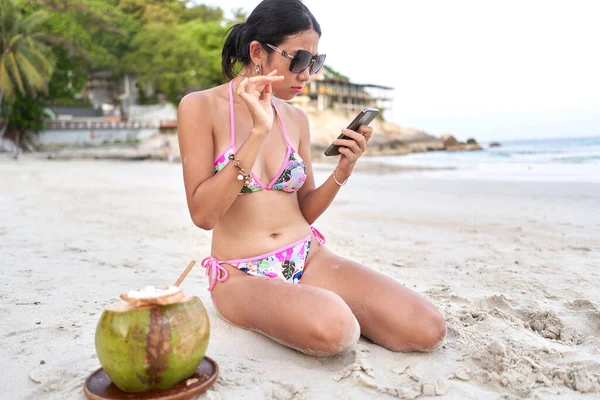 Genç flamalı, tropik bir plajda cep telefonu kullanıyor.