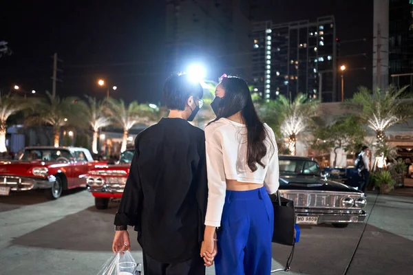Lésbicas casal de pé em um estacionamento cheio de carros antigos em uma feira da noite — Fotografia de Stock