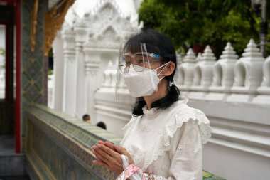Bangkok, Tayland, 16 Şubat 2022, Makha Bucha Günü 'nde tapınakta dua eden plastik yüzlü genç kadın.