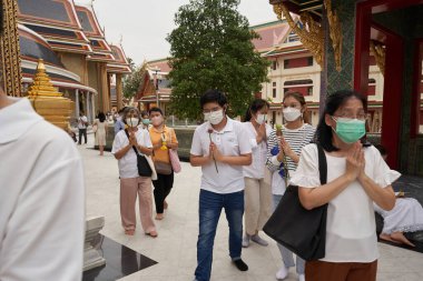 Bangkok, Tayland, 16 Şubat 2022: Budist festivali sırasında bir Budist tapınağının önünde namaz kılan bir grup insan