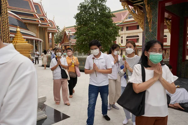 Bangkok, Tayland, 16 Şubat 2022: Budist festivali sırasında bir Budist tapınağının önünde namaz kılan bir grup insan