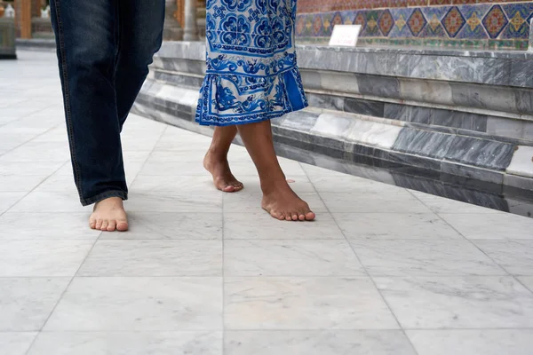 Cropped photo of the bare feet of a transgender couple walking outside a Buddhist temple in Thailand