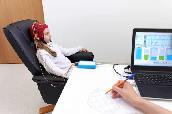 Doctor controlling the responses of the brain of a patient during a biofeedback therapy