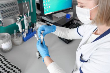 Hastane laboratuvar teknisyeni elinde kan örnekleri ile santrifüj reaksiyon kabının yanında.