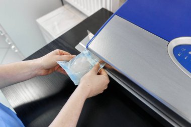 Bir işçinin elleri hastanede ısı yalıtımı makinesiyle plastik poşeti mühürlüyor.