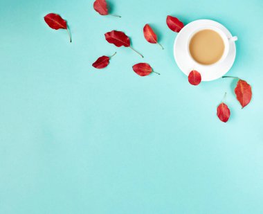 Sonbahar düz arka planı maviye uzanıyordu. Gerçekçi kırmızı yapraklı kompozisyon ve bir fincan kahve. Merhaba Ekim konsepti. Boşluğu kopyala