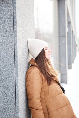 Doğal çilli bir kadın şehirde kışın tadını çıkarıyor. Kar taneleriyle birlikte kış portresi. Milenyum Esmer Kadın Moda Kıyafetli