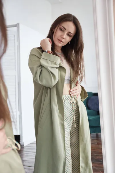 Kadın aynaya bakar ve kilo verdikten sonra ya da hamileliğinin ilk ayında vücudunu kontrol eder.