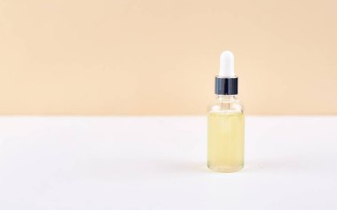 Beyaz ve sarı arka planda, damlatıcı şişedeki temel yağ. Doğal tıp konsepti. Aromaterapi 