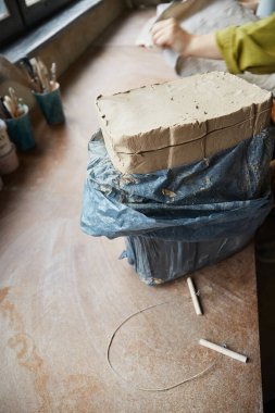 Masada gri kil blok var. Çömlek atölyesinde çalışan kadın seramik. Çömlek yapma süreci. Usta seramist onun stüdyosunda çalışıyor.