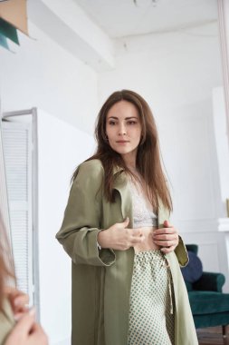 Kadın aynaya bakar ve kilo verdikten sonra ya da hamileliğinin ilk ayında vücudunu kontrol eder.