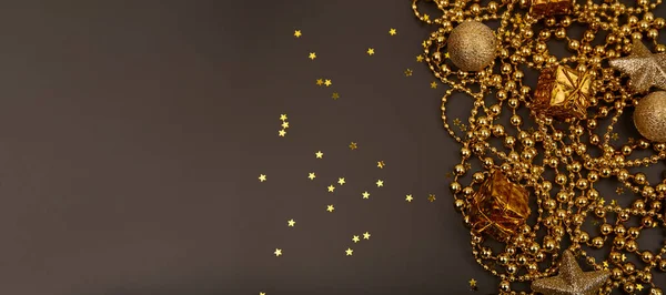 Karanlık arka planda hediye kutuları olan altın Noel süsleri. Tebrik kartı şablonu. Boşluğu kopyala