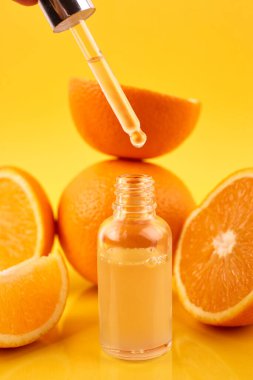 Turuncu esanslı boru yağı şişenin üzerinde ve sarı arka planda portakallar. Doğal tıp konsepti. Aromaterapi