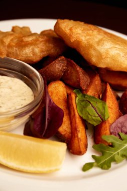 Bir tabakta haşlanmış balık ve pubda tahta bir masada patates kızartması. Sağlıksız yiyecekler
