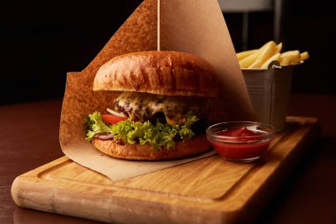 Bardaki ahşap masada patates kızartmalı taze etli burger.