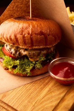 Bardaki ahşap masada patates kızartmalı taze etli burger.