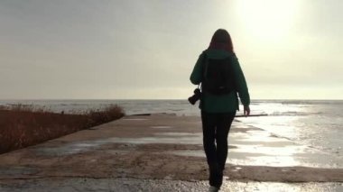 Girl walks by the frozen sea at sunset. Winter. Sea of Azov.