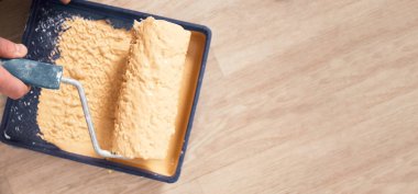 Parlak ahşap arka planda boya tepsisi ve boya silindiri. Yenileme konsepti.