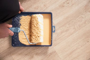 Parlak ahşap arka planda boya tepsisi ve boya silindiri. Yenileme konsepti.