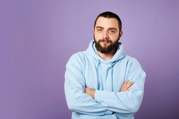 Mutlu sakallı adam mor arka planda mavi kazak giyer. Dostça gülümseme. Boşluğu kopyala