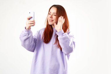 Mor kazaklı beyaz bir kadın. Doğal görünüş. Gülümsüyor. Uzun kızıl saçlı. Beyaz arkaplan