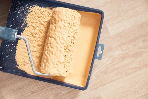 Parlak ahşap arka planda boya tepsisi ve boya silindiri. Yenileme konsepti.