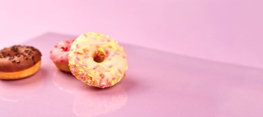 Mor arka planda renkli çörekler. Boşluğu kopyala