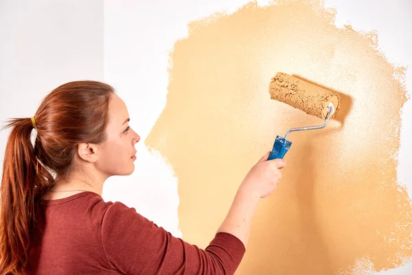 Smiling caucasian woman painting interior wall of home. Renovation apartment. repair and redecoration concept. copy space