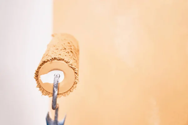 Paint Roller Mit Pfirsichfarbener Farbe Auf Einer Weißen Wand Renovierung — Stockfoto