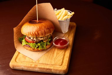 Bardaki ahşap masada patates kızartmalı taze etli burger.