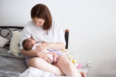 Anne yeni doğmuş bebeğini emziriyor. Gerçekçi ev portresi