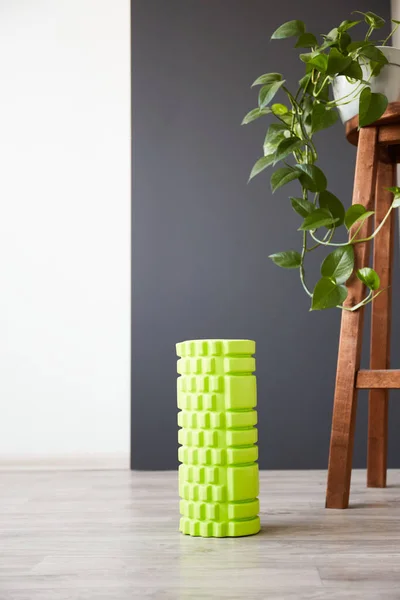 Green foam sport roller for self-massage. Home fitness accessories. Flexibility and mobility, body strength