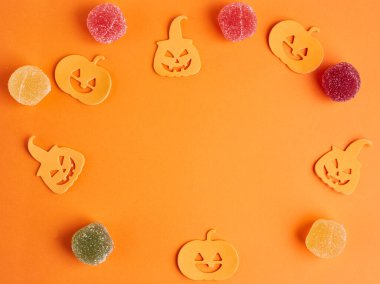 Cadılar Bayramı süslemeleri, balkabakları, turuncu arka planda şekerler. Cadılar Bayramı partisi tebrik kartı. Uzayı kopyala Düz yatıyordu, üstten, yukarıdan..