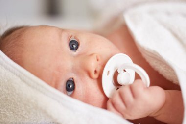 newborn one month old baby boy with nipple. smiling baby