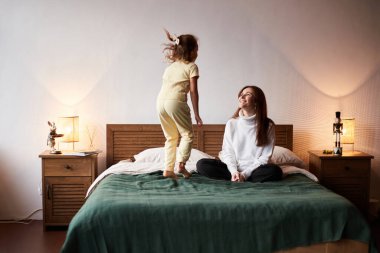 Little caucasian girl have fun with mother. Jumping on bed christmas morning. Happy family christmas concept