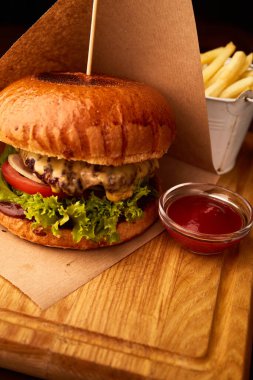Bardaki ahşap masada patates kızartmalı taze etli burger.