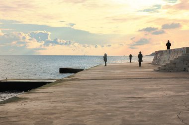 Gün batımında deniz kenarında. Denizin arka planında birkaç figür