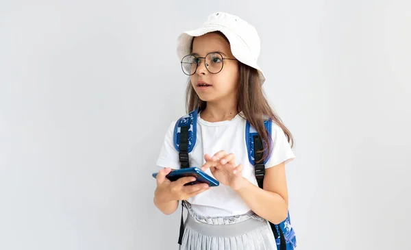 모자를 티셔츠를 안경을 배낭을 여학생은 배경으로 핸드폰을 스마트폰으로 온라인 게임을 스톡 사진