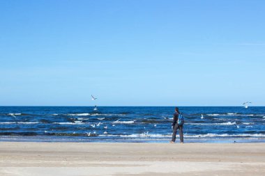 Blue Baltic sea, man is walking on the beach. 