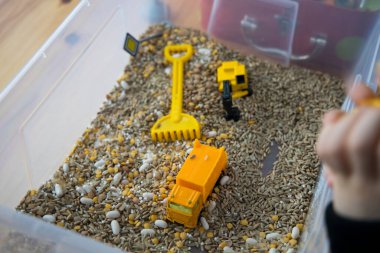 Playing toy cars in a box with grains