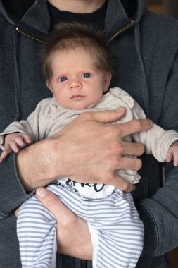 Bir baba kucağında yeni doğan tatlı oğlunu tutuyor.