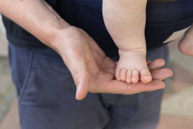 Bir baba tatlı oğlunu tutuyor, bir el ve bir ayak.